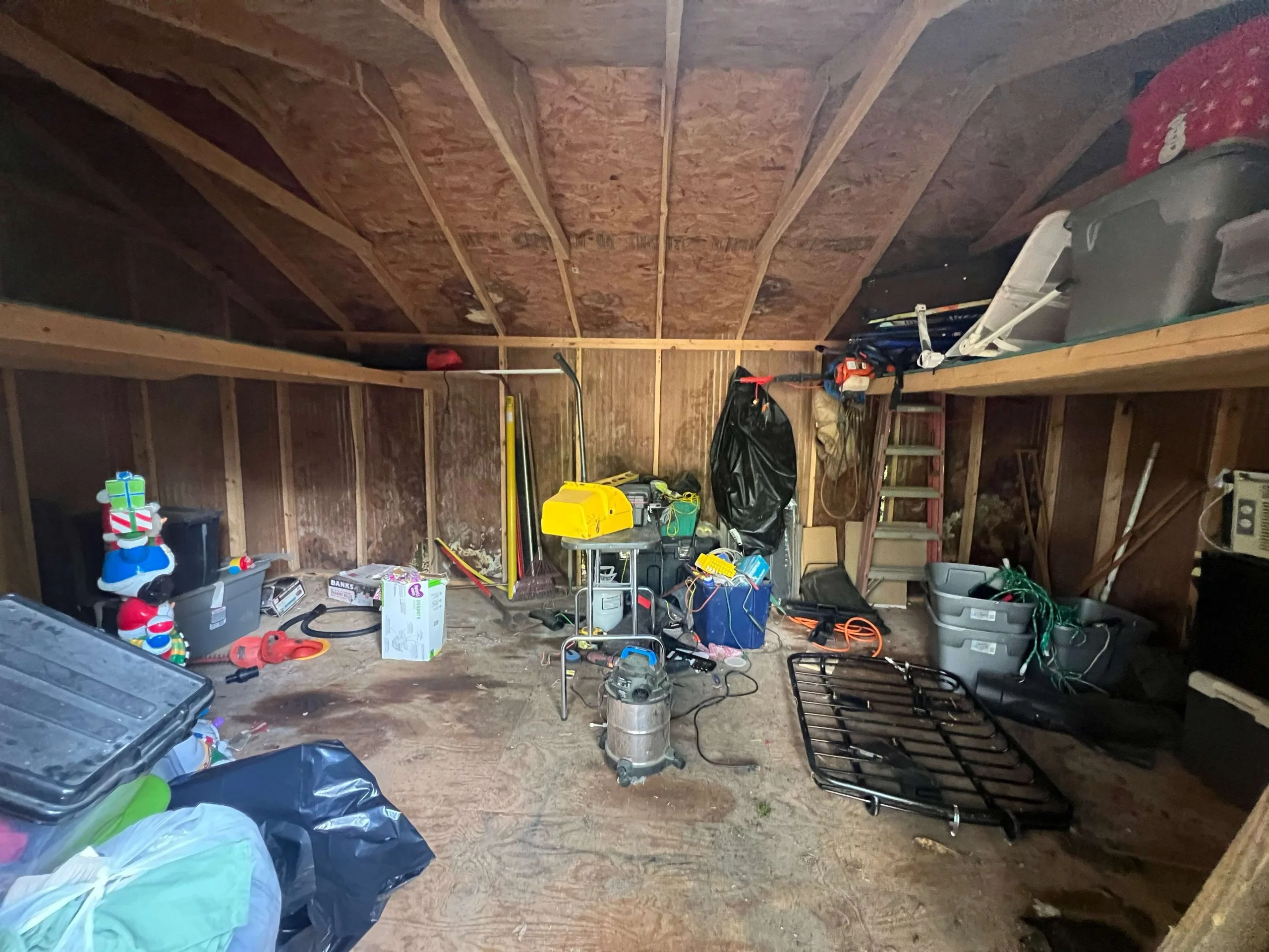 Cluttered attic space with stored items and debris in a property sold as-is for cash